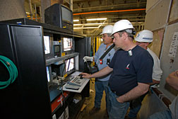 Cervando Castro (left) and Keith Anderson operate the remote crane control for the NuMI beam line at Fermilab.