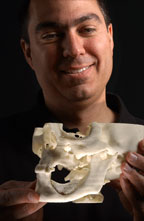 Pain-saving device brings pleasure to creator: Sandia researcher Joe Cesarano admires the perfect fit of his team's Robocasted implant set in the jawbone of a manufactured skull.