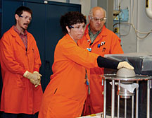 With her gloved hand on a uranium test assembly, Barbara Kr�gfuss of Y-12 participates in a nuclear criticality training exercise with LLNL certified fissile material handler Nolan Lomba (right) as Mark Lee of the DOE Livermore Site Office looks on.