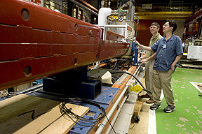 Physicists examine the spare Tevatron magnet used in the GammeV experiment.