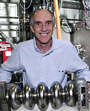 Gwyn Williams holding an accelerator component inside JLab's FEL.