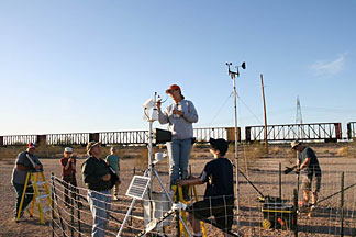 NREL senior engineer Steve Wilcox (left foreground, green shirt) looks up as technicians make the final adjustments to the first rotating shadowband radiometer in a planned solar measurement network in the Southwest.
