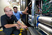 NREL engineers Sudipta Chakraborty and Bill Kramer examine the design of the power block at a laboratory at NREL. The large cylinders are the DC bus capacitors. The digital controller is on the green board. Credit: Dennis Schroeder
