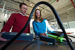 NREL engineers Dane Christensen and Bethany Sparn test advanced power strips at NREL's Automated Home Energy Management Laboratory. The lab enables researchers to study the complex interactions of appliances and other devices in connection to the energy grid. Credit: Dennis Schroeder