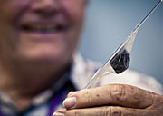 2012-165-8205-METEORITE, Sample of a meteorite that fell over the Sierra Nevada last April, held up by SSRL regular Tom Cahill of the University of California-Davis' DELTA Group. (Photo by Brad Plummer)