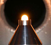 A metal oxide drop levitated in a flow of high-purity argon gas. The sample is being heated from above with a laser beam that can heat it more than 2500 degrees centigrade. The sample is held in a special "levitation nozzle" installed in the NOMAD beam line.