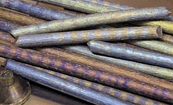 Extruded Europium (Eu) Metal. The colors arise from various levels of oxidation. The banding is from surface texture variation arising from the extrusion process. Photo by the Materials Preparation Center.
