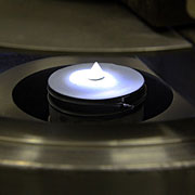 An interior glimpse of centrifugal atomization apparatus constructed at the Ames Laboratory, showing the spinning disc. The disc will intercept a stream of molten calcium and fling off a spray of fine droplets. The droplets, less than one hundred microns in diameter, solidify as they cool and are captured in a quenching bath of hydrocarbon oil, which prevents the calcium from reacting.