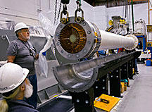 PPPL technicians lower the fiberglass-wrapped bundle of 36 magnetic field conductors into the VPI mold.