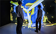 In the Energy Systems Integration Facility (ESIF) Insight Center, NREL Senior Engineer Pat Moriarty, left, and NREL Senior Engineer Paul Fleming review velocity (blue) and turbulence (yellow) in a simulation of the Lillgrund Wind Farm in Denmark. Photo by Dennis Schroeder, NREL