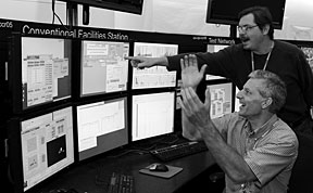 Michael Plum (sitting) and Viatcheslav Danilov (standing) react as the SNS beam power readout goes to seven figures.