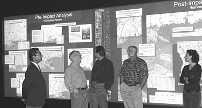 Members of the Georgraphic Information Science & Technology group (from left, Budhendra Bharduri, Phil Colemen, project leader Mark Tuttle, Eddie Bright and Marie Minner) examine maps displayed in the EVEREST visualization lab.